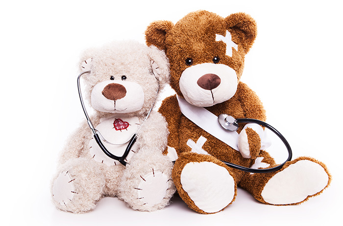 Zwei traurigeTeddybären sitzen nebeneinander, mit Pflastern verbunden und Stethoskop