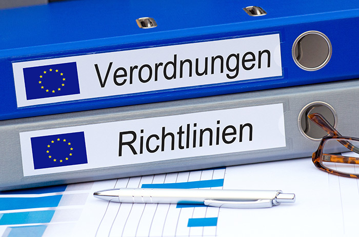 Zwei Ordner im Büro, ein blauer mit der Aufschrift "EU Verordnungen" und darunter ein grauer mit der Aufschrift "EU Richtlinien".